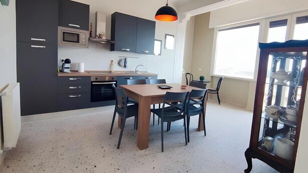 A modern kitchen with dark cabinets, a microwave, and a dining area with a wooden table and chairs.