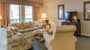 Une chambre d’hôtel équipée d’un canapé, d’un fauteuil, d’une télévision et d’un ventilateur de plafond.