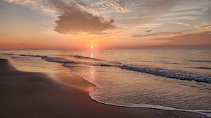 Una playa con olas y un atardecer.