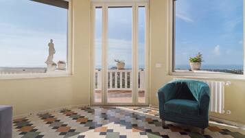 Ein Zimmer mit Fliesenboden, einem Stuhl, einer Statue und Blick durch eine Glastür.