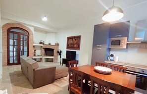 A living room with a fireplace, a dining area with a table and chairs, and a kitchen with modern appliances.