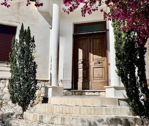A building with a wooden door, white columns, and a stone staircase leading to the entrance.