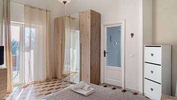 Ein Schlafzimmer mit einem Bett, einem Kleiderschrank, einer Tür mit Fenster und einer Kandelaber.