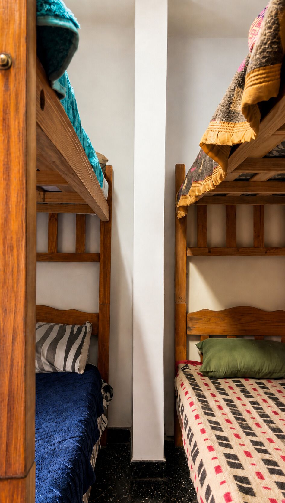 Une chambre de dortoir avec deux lits superposés, une armoire en bois et un pilier blanc.