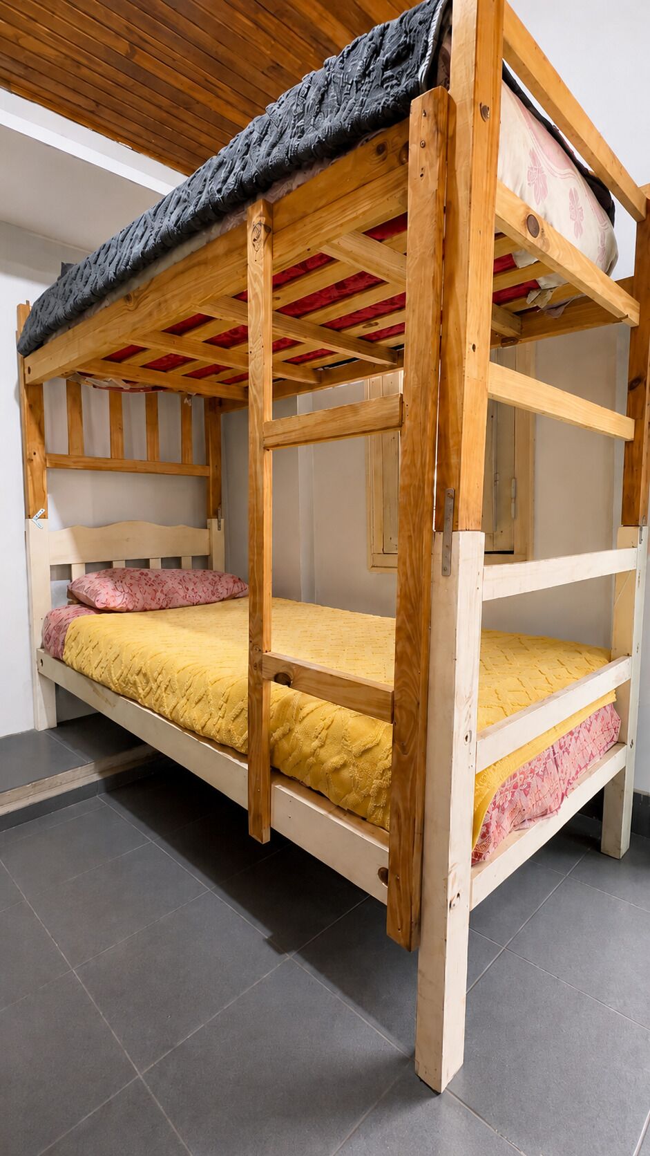 A bunk bed with a wooden frame and a mattress with a patterned cover.