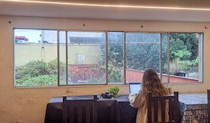 A room with a large window, a table with a camera, and a chair. - TUHOSTEL (San Miguel de Tucumán)
