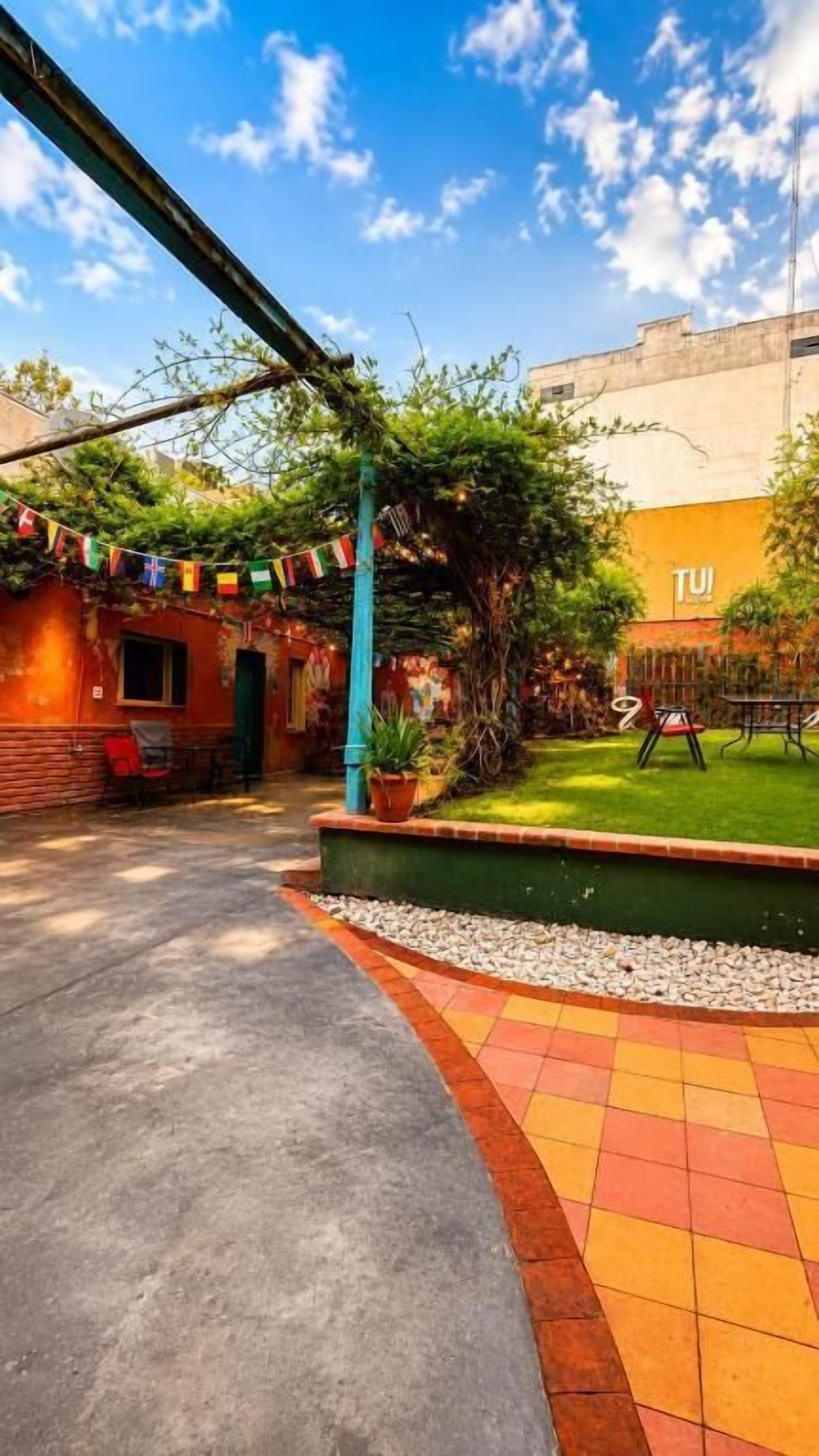 Un patio con un camino empedrado, un pequeño edificio de ladrillo y un área con césped.