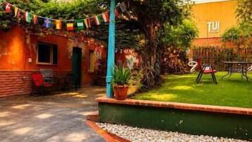 Un patio con un camino empedrado, un pequeño edificio de ladrillo y un área con césped.