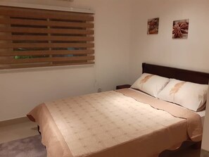A bedroom with a bed, a window with blinds, and two wall-mounted pictures. - Charming 4-bedroom townhome with AC, pool, and Wi-Fi in vibrant East Legon (Accra)