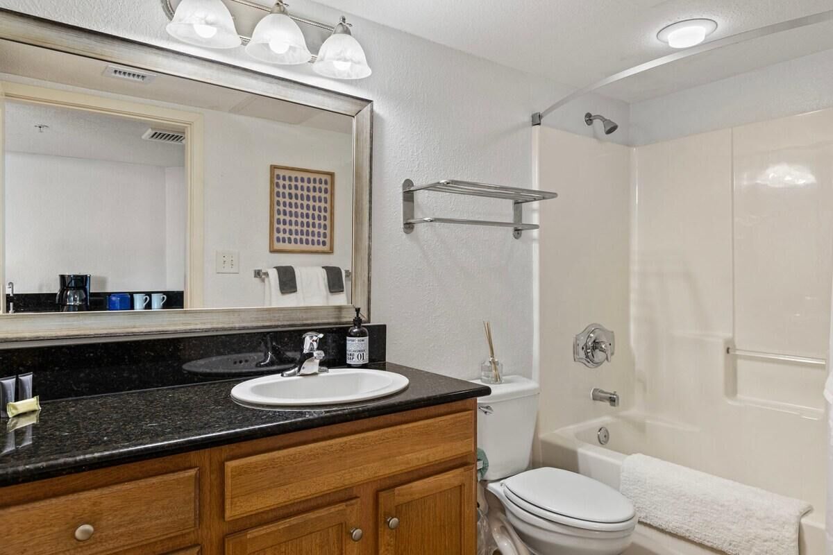 Ein Badezimmer mit Waschbecken, Spiegel, Waschtisch, Toilette und Dusche.