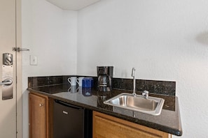 Una cocina funcional con lavamanos, cafetera y lavavajillas.