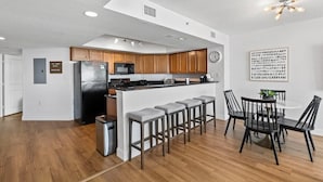 Eine moderne Küche mit Holzausstattung, einem schwarzen Kühlschrank und einer Bar mit Hockern.