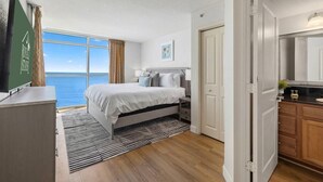 Ein Schlafzimmer mit großem Fenster, einem Bett, einem Nachttisch und Meerblick.