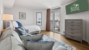 Ein modernes Schlafzimmer mit Bett, Sofa, Kommode und einem Balkon mit Stuhl.