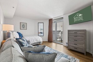 Ett modernt sovrum med en säng, en soffa, en byrå och en balkong med en stol.