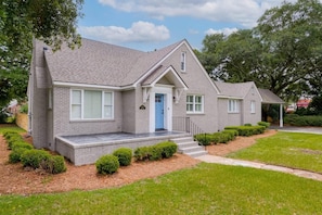 A two-story house with a grey brick exterior, a blue front door, and a small porch with steps. - Palmetto Grove, Walk to Shem Creek, Mins to Dwt (Mount Pleasant)