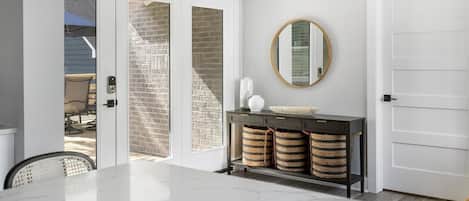A modern kitchen with a marble countertop, a black console table with baskets, and a round mirror on the wall.