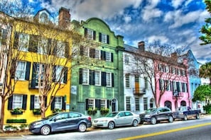 Una hilera de edificios históricos coloridos con coches estacionados a lo largo de una calle.