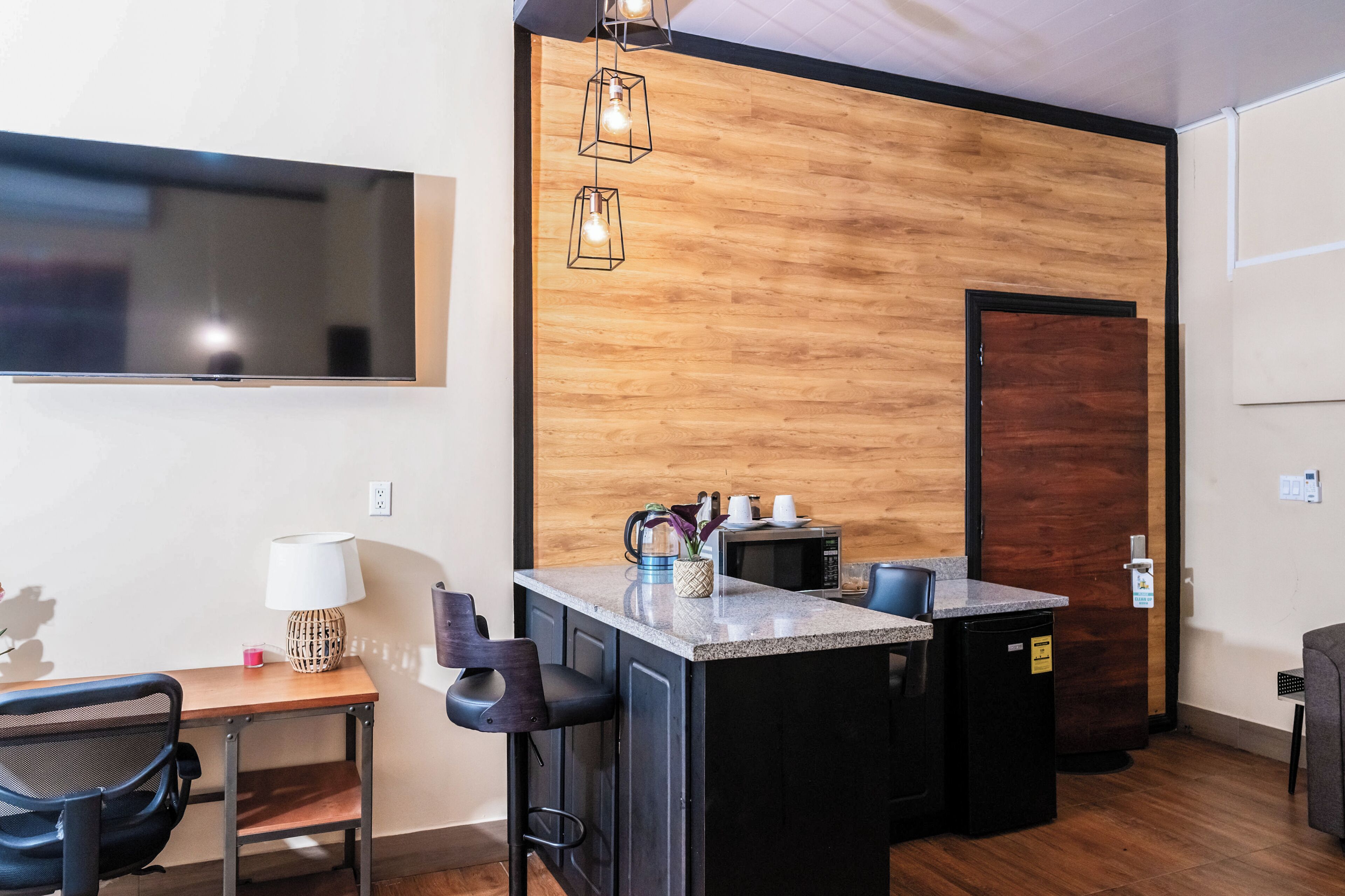 Eine kompakte Küche mit einer Holz-Akzentwand, einer integrierten Mikrowelle und einer kleinen Barzeile.