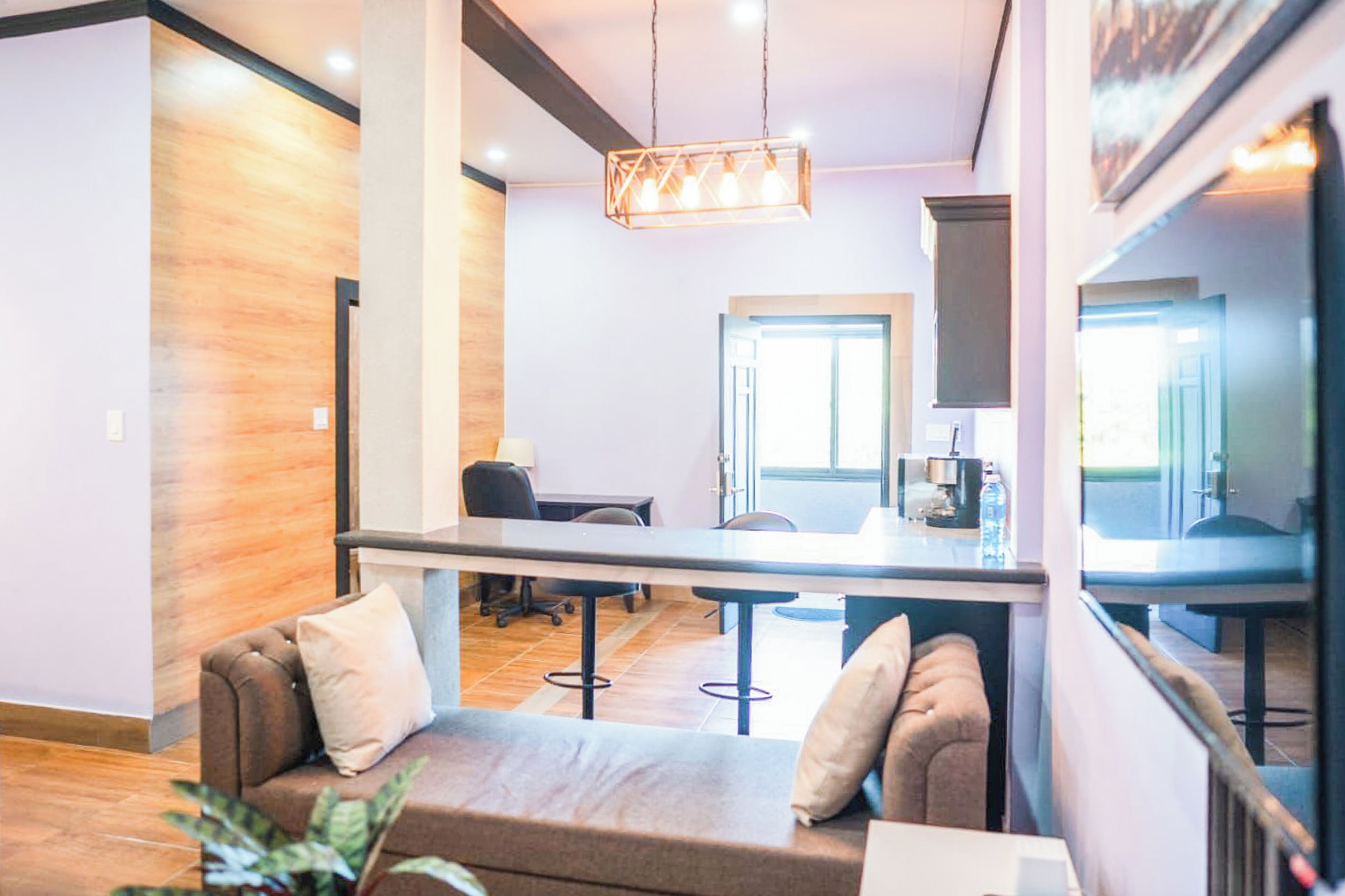 A modern interior with a sofa, a dining area, and a kitchen visible through an open space.
