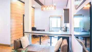 A modern interior with a sofa, a dining area, and a kitchen visible through an open space.