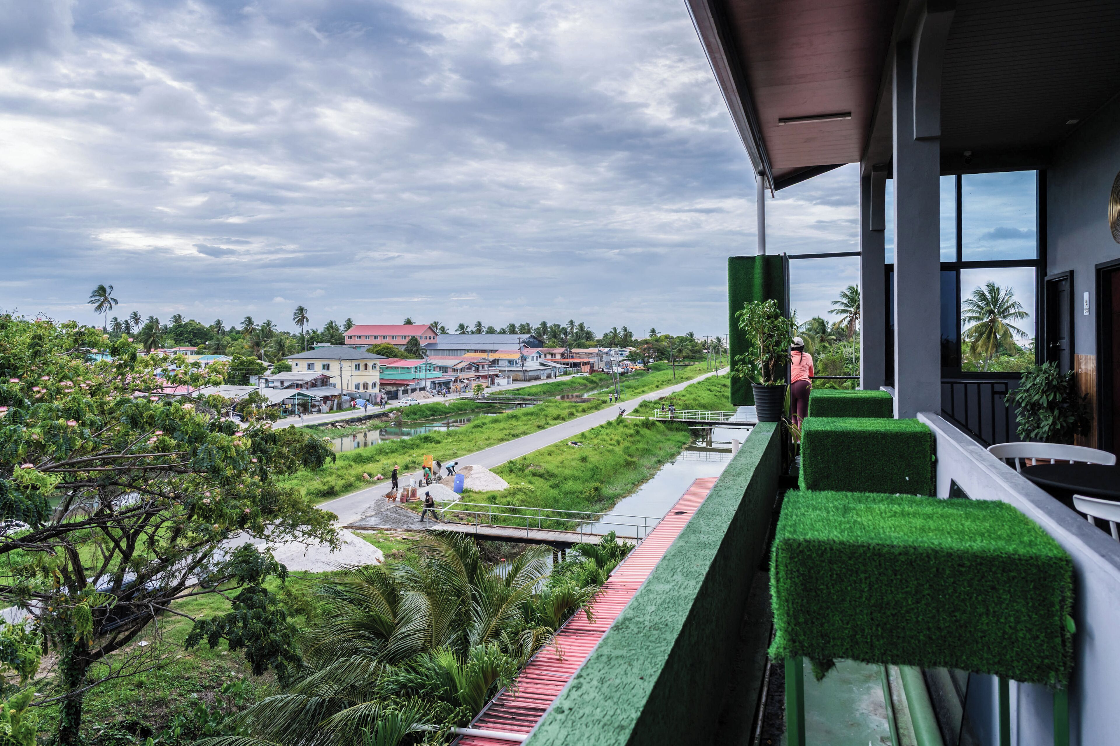 A balcony with a view of a river, greenery, and buildings in the distance.