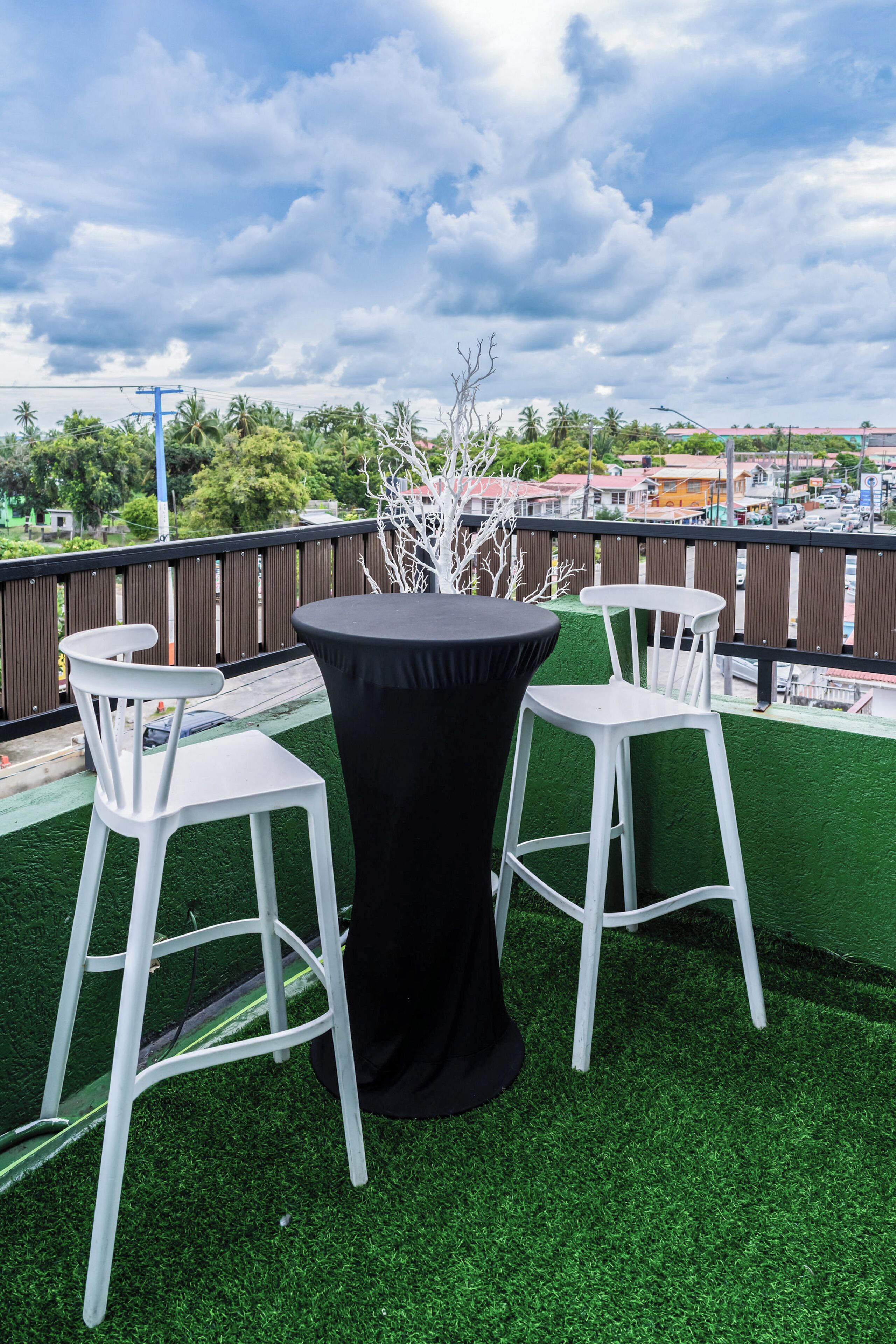 Une terrasse sur le toit, avec deux tabourets de bar blancs et une table noire, le tout entouré d’une rambarde en bois.