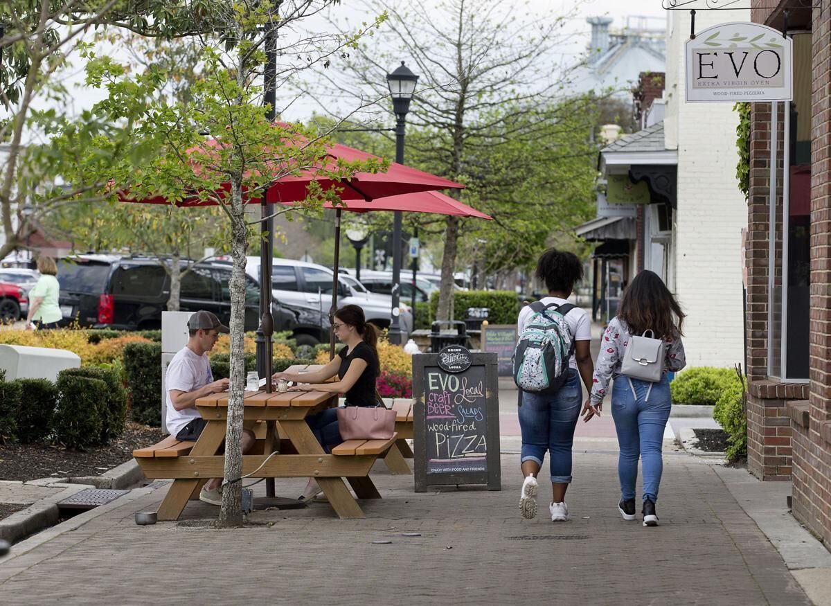 Eine Straßenszene mit Außenbereich eines Restaurants, einem Schild für 'EVO' und geparkten Autos.