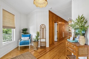 Um quarto com piso de madeira, uma cadeira azul, uma cesta de vime e uma porta de madeira.
