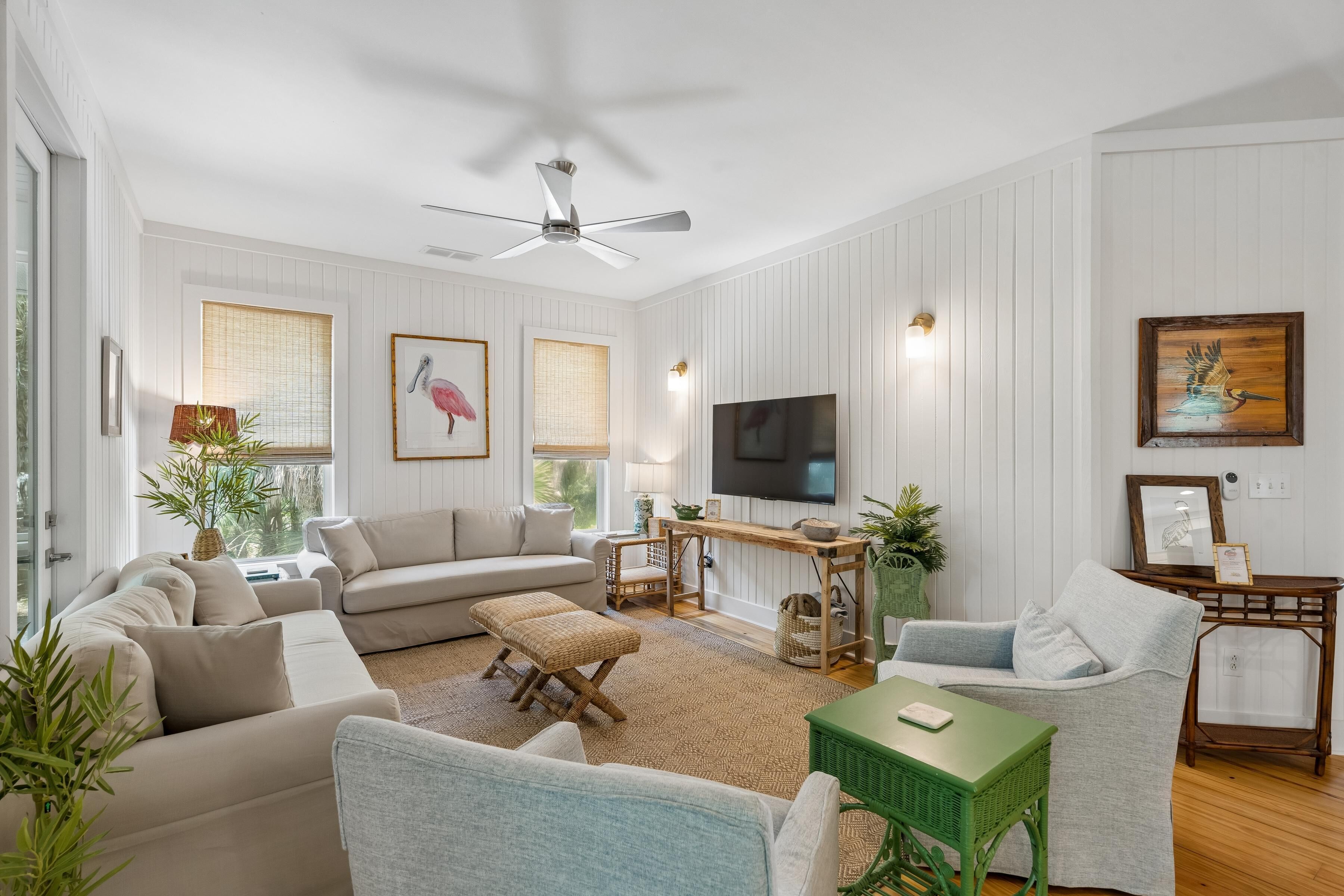 A living room with a ceiling fan, a television, and a large window with a view.
