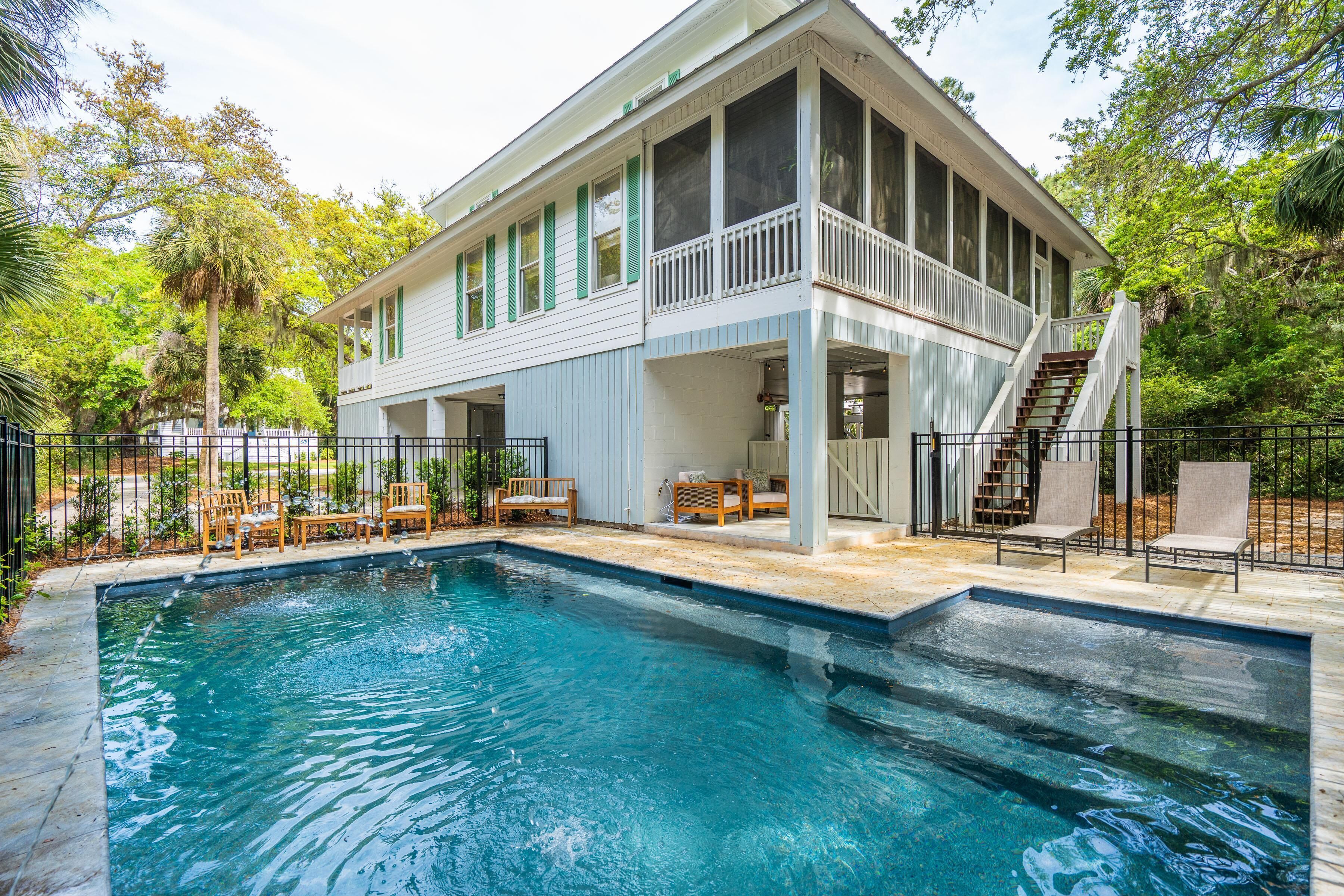 A house with a swimming pool, a covered porch, and a staircase leading to a balcony.