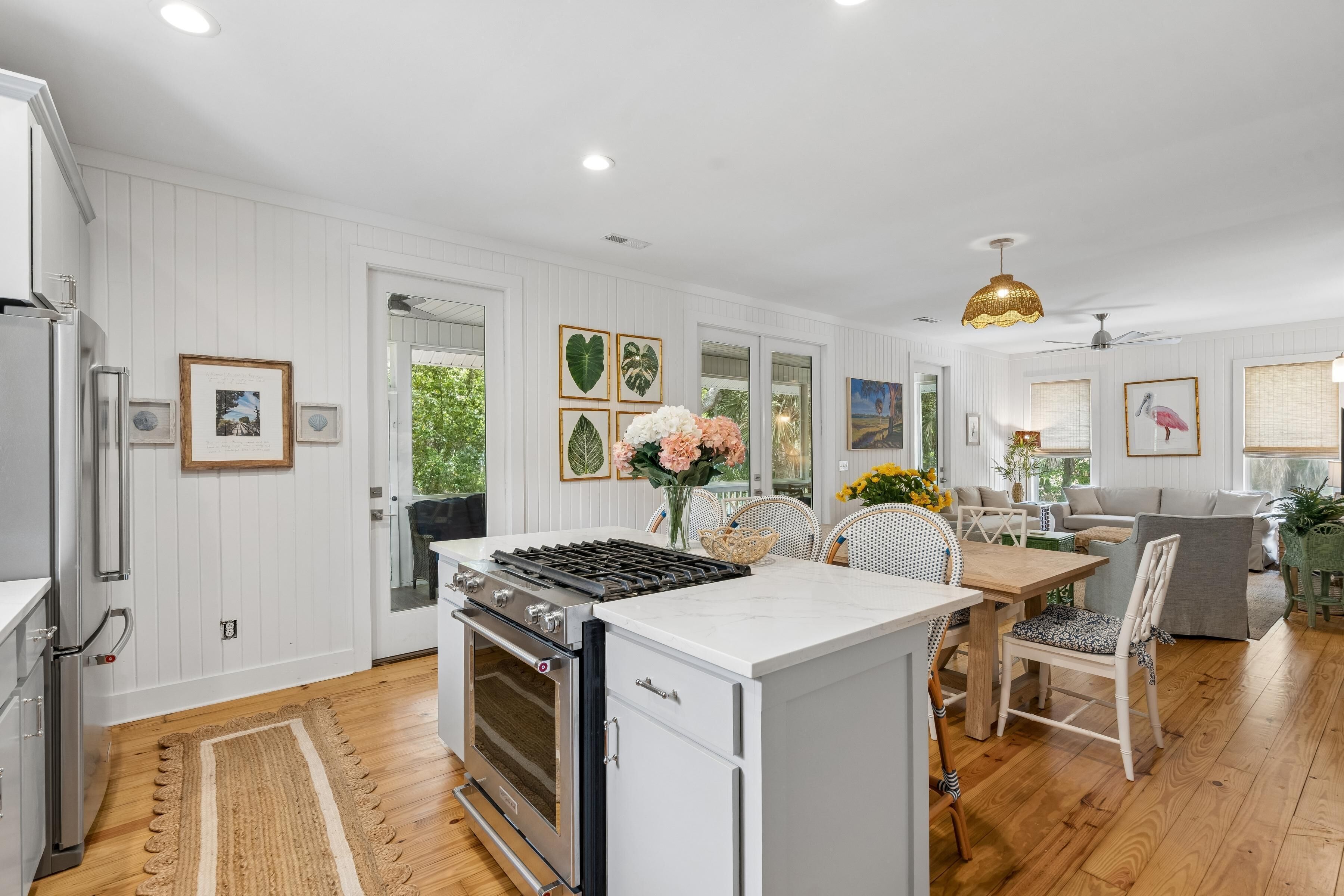 A modern kitchen with white cabinetry, a built-in stove, and a dining area with a wooden table and chairs.