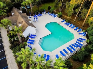 An aerial view of a swimming pool surrounded by blue lounge chairs, with a small building and lush greenery nearby. - Boho Soco- 8 Mins to Credit One, 20 Mins to Dtwn (Charleston)