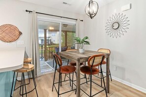Comedor con una mesa de madera y cuatro sillas, una planta en maceta y un adorno en la pared.