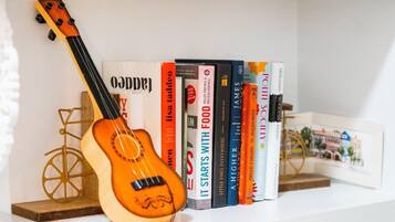Una estantería con una guitarra, libros y un adorno pequeño.