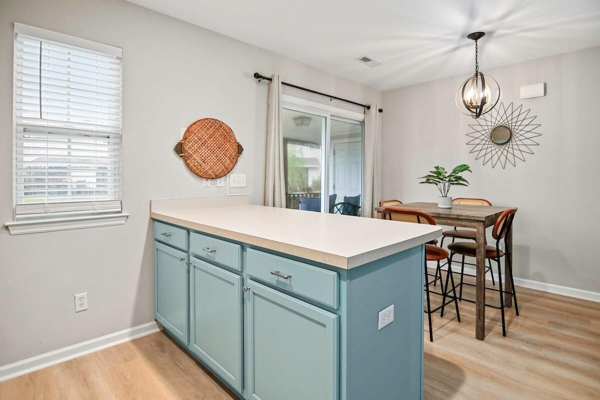 A kitchen with a central island, a dining area with a table and chairs, and a ceiling fan.