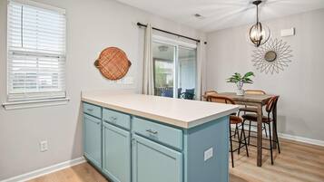 A kitchen with a central island, a dining area with a table and chairs, and a ceiling fan.