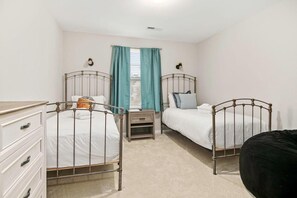 A bedroom with two metal-framed beds, a dresser, and a window with curtains. - Boho Soco- 8 Mins to Credit One, 20 Mins to Dtwn (Charleston)