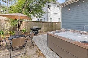 An outdoor patio with a hot tub, a grill, and a table with chairs. - Shem Creek House- 5 Mins to Dtwn & Beach Hot Tub (Mount Pleasant)