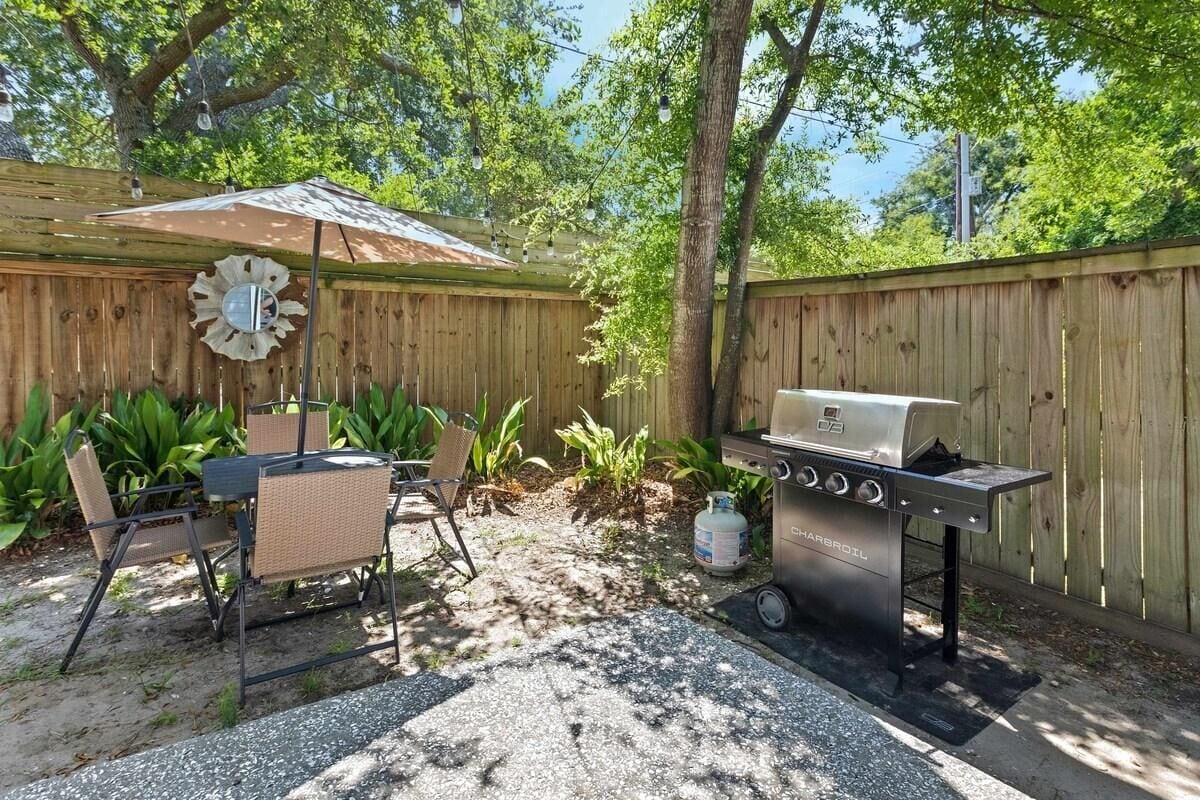 A backyard with a barbecue grill, a table with chairs, and a decorative mirror.