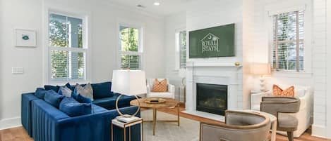 A living room with a blue sectional sofa, a fireplace, and a television mounted on the wall.