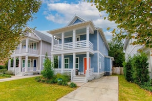 A two-story residential house with a front porch, a second-floor balcony, and a red door. - Shem Creek House- 5 Mins to Dtwn & Beach Hot Tub (Mount Pleasant)