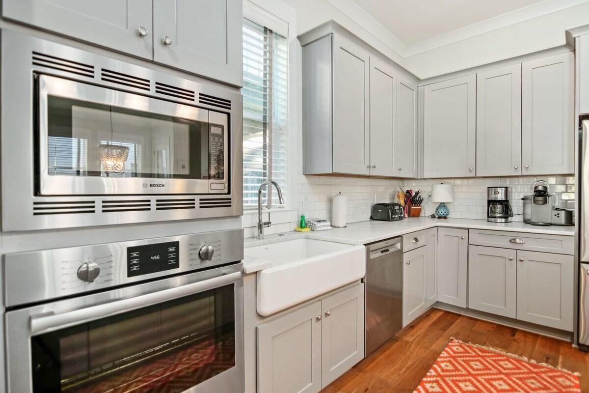 A modern kitchen with stainless steel appliances, white cabinets, and a wooden floor.