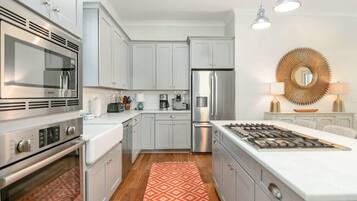 A modern kitchen with white cabinets, stainless steel appliances, and a central island.