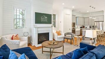 A spacious living room with a fireplace, a dining area, and a kitchen.