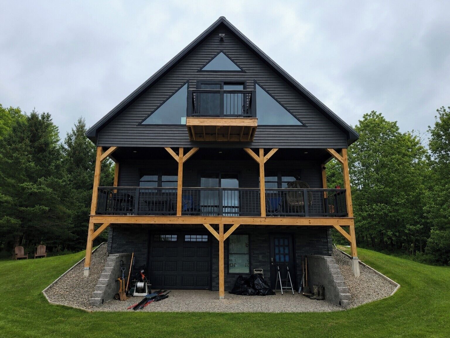 A two-story building with a balcony, a garage, and a stone foundation.