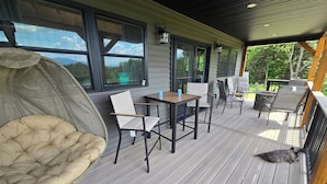 Eine überdachte Terrasse im Freien mit gepolstertem Stuhl, Tisch und Stühlen.