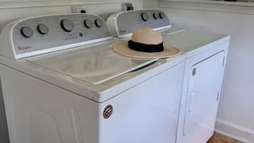 A Whirlpool washer and dryer in a kitchen with a window above the appliances.
