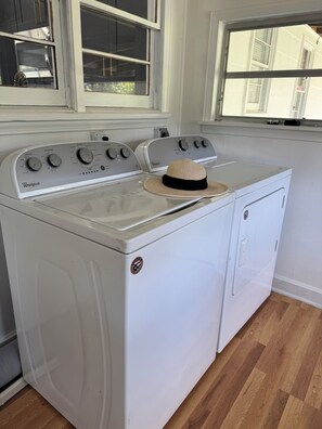 A Whirlpool washer and dryer in a kitchen with a window above the appliances.