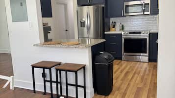 Une cuisine moderne avec des meubles de couleur sombre, des appareils en acier inoxydable et un coin repas en bois.